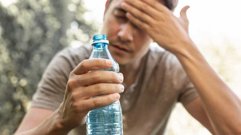 Ein Mann sitzt da und hält eine Flasche Wasser in der Hand