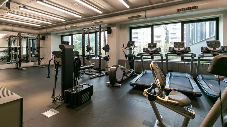 Innenraum eines Fitnessstudios mit Laufbändern, Gewichten und stationären Fahrrädern