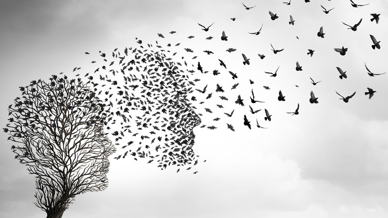 Todeskonzept eines Baumes mit Ästen, die wie ein Gesichtsprofil geformt sind, und Vögeln, die in einer Gruppe davonfliegen, die in wenige verblasst