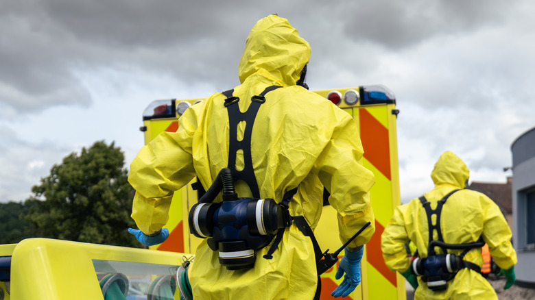 Ein paar Leute in Schutzanzügen gehen von der Kamera weg.