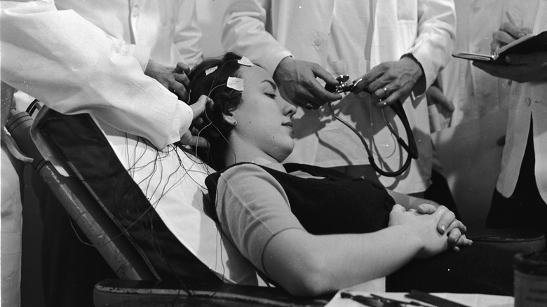 Wissenschaftler platzieren Elektroden am Kopf einer Frau.