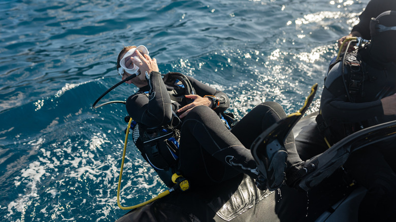 Männlicher Taucher in Tauchausrüstung rollt rückwärts vom Boot ins Wasser